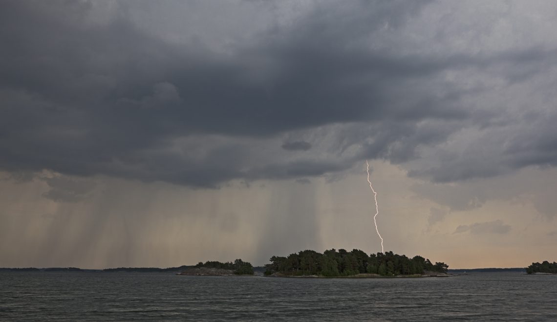 Merinäkymä jossa salama iskee saaren taakse